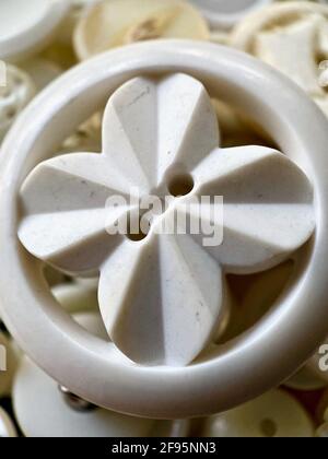 Close up or macro photo of one large, white bakelite or celluloid button with a background of other white buttons. Round button, two holes and flower Stock Photo
