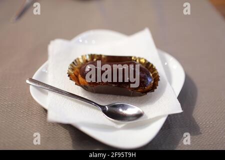 Chocolate eclair on the white plate in a cafe Stock Photo