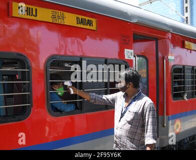 A healthcare worker checks temperature of a passenger at Dadar Terminus in Mumbai.Due to the rise in coronavirus cases in Maharashtra state, passengers arriving from other states have to undergo health check up at the railway station before they can proceed to their respective destination in the city. Stock Photo