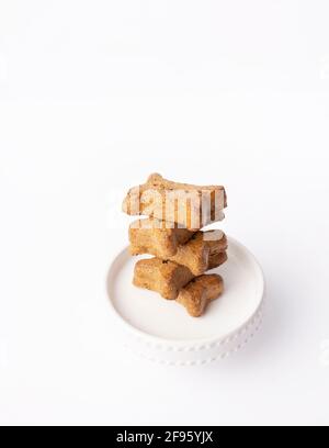 Stack of five bone shaped dog treats on mini cake pedestal on white Stock Photo