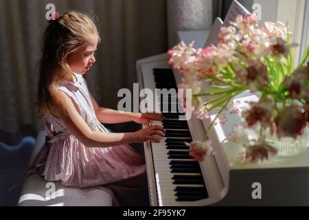 Young girl practicing piano at home. Beautiful scene. Indoor activity. Stock Photo