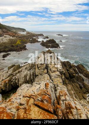 View along the tilted and layered, zagged rocks of the south coast of South Africa in the Tsitsikamma section of the Garden Route National Park Stock Photo