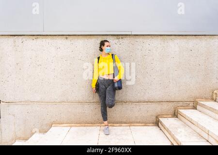 Active woman with sportswear tablet and mask waiting on stairs Stock Photo