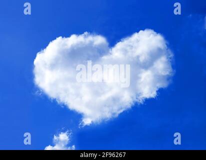Heart shaped fluffy cumulus clouds floating on vivid blue sky Stock Photo