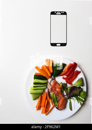 smartphone frame & white plate with vegetables & salmon on white table Stock Photo
