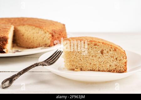 Close up of a slice of homemade sponge cake on a white wooden table Stock Photo