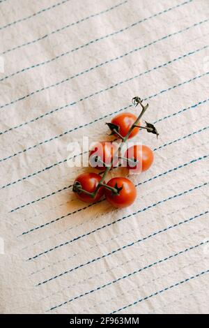 Cluster of fresh and organic cherry tomatoes on a rustic white tablecloth Stock Photo