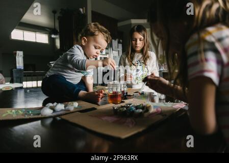 Kids working on an art project at home making fish during homeschool Stock Photo