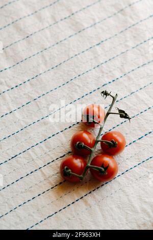 Cluster of fresh and organic cherry tomatoes on a rustic white tablecloth. Copy space Stock Photo