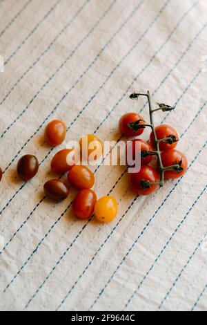 Fresh and organic cherry tomatoes on a rustic white tablecloth.Top view Stock Photo