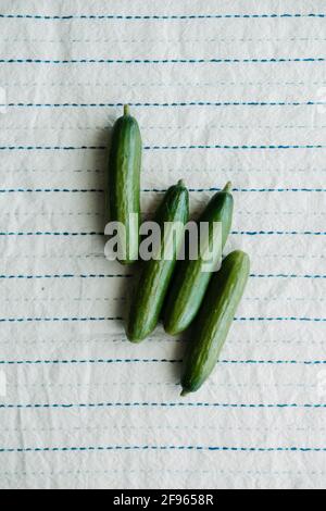 Raw organic mini cocktail green cucumbers on rustic white tablecloth. Top view Stock Photo