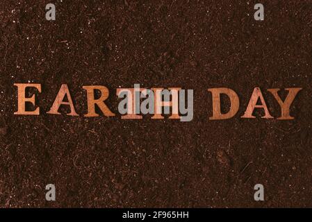 Earth day inscription with text made of wood cutout words on brown natural soil background. Stock Photo