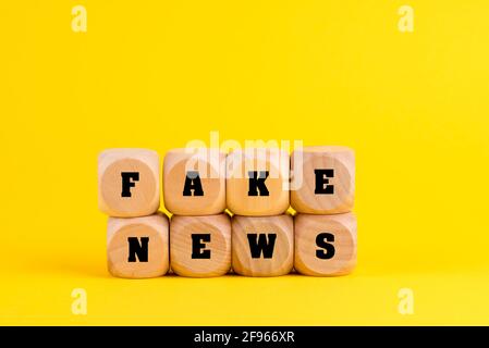 Phrase FAKE NEWS formed with wooden blocks in the yellow background Stock Photo