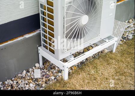 Air conditioner compressor mounted on the wall of a house, outdoor shot Stock Photo