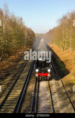 British Rail Merchant Navy Class 4-6-2 no 35028 'Clan Line' steam locomotive hauling a special train on a long straight rail section in Hampshire, UK