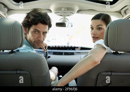 Woman and man are sitting in the car and looking at the back seat Stock Photo