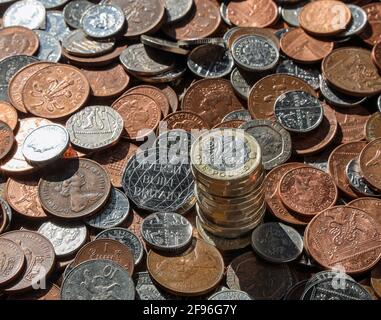 British metric coins on a table, with a pile of one pound coins tail side up Stock Photo