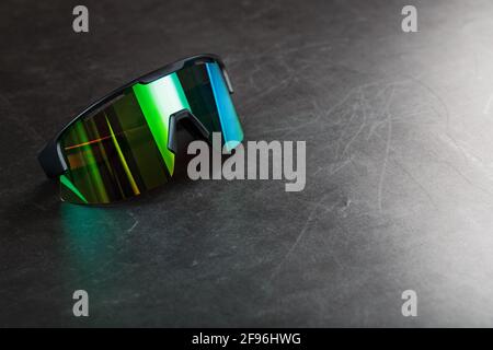 Sports glasses with a green mirrored lens on a black textured background. Free space. Stock Photo
