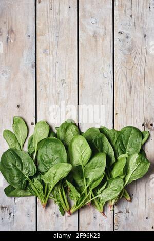 Green spinach leaves on a wooden surface, top view. Stock Photo