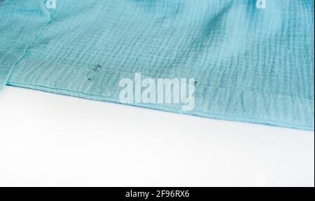 Sewing Turquoise Cotton. Metal pins will pin the hem of the fabric. White background for copy space. Sewing themes. Stock Photo