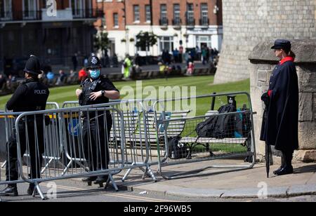 An armed police officer wearing a mask and guard stand in front of Windsor Castle, following the April 9th death of Britain's Prince Philip, Duke of Edinburgh who died at the age of 99. Stock Photo