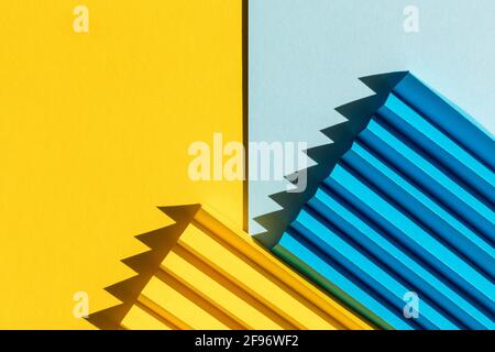 Abstract blue and yellow colored paper texture. Folded paper with harsh sun shadows, geometric shapes and lines. Minimalist background. Flat lay. Copy Stock Photo