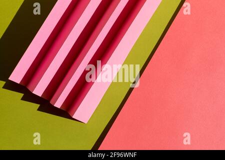 Abstract green and pink colored paper texture. Folded paper with harsh sun shadows, geometric shapes and lines. Minimalist background. Flat lay. Copy Stock Photo