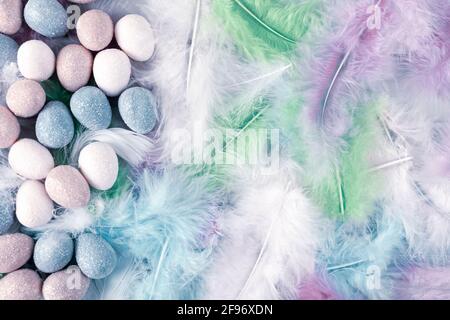 Happy Easter Holiday. Decorative Easter eggs on colorful feathers background. Copy space. Flat lay. Stock Photo