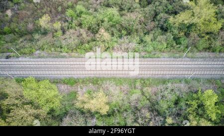 Top down view of rural railway passing through the forest landscape, photographed with drone from above Stock Photo