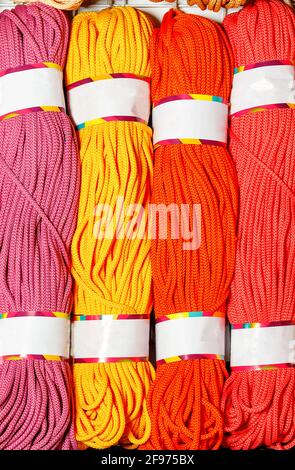 Rolls of bright pink, red, yellow and crimson polyester cord, rolled. Vertical image, close-up, copy space. Stock Photo