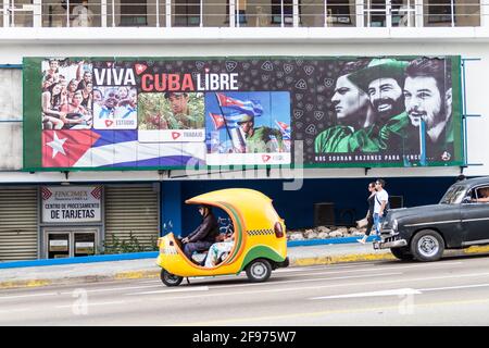 HAVANA, CUBA - FEB 21, 2016: Coco taxi and a propagandistic poster in Vedado neighborhood of Havana. Stock Photo