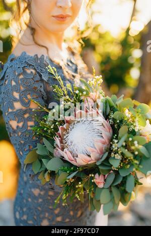 The bride in a stylish blue dress with wedding bouquet standing outdoors, close-up Stock Photo