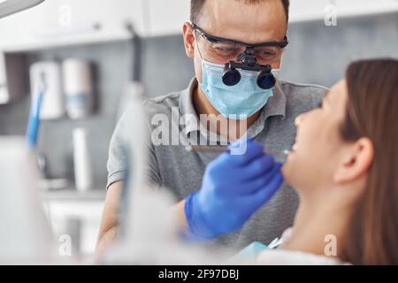 Modern dental surgery, face of a female doctor working on a patient. Dental implantation operation on a patient at dentistry office Stock Photo