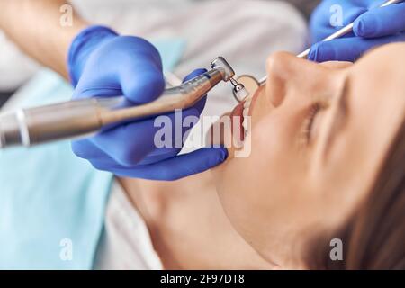 Female patient at dental procedure, doctor using dental instruments in modern dental clinic, close up. Stock Photo