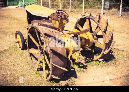 An old, wheathered, and abandoned Ford Fordson tractor rusting away on desicated grass. Stock Photo
