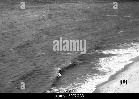 Black and white shot of the sea, waves crashing ashore, from the top of a seaside bluff. Stock Photo