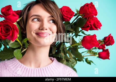 Photo of sweet shiny lady dressed purple pullover holding back red flowers looking empty space isolated teal color background Stock Photo