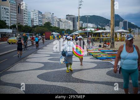 Street seller on the famous Avenida Atlantic with the pattern from Oscar niemeyer at copacabana beach in Rio de Janeiro, Brazil. In the background the famous sugar loaf mountain Stock Photo