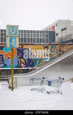 Essen, North Rhine-Westphalia, Germany - onset of winter in the Ruhr area, shopping trolleys stand in the snow on an escalator to the subway station. Stock Photo