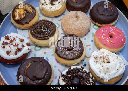A delicious selection of colourful doughnuts including a chocolate one with sprinkles Stock Photo