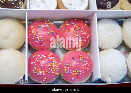A delicious box selection of colourful doughnuts, including pink and chocolate ones with sprinkles Stock Photo