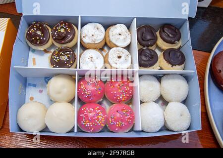 A delicious box selection of colourful doughnuts, including pink and chocolate ones with sprinkles Stock Photo