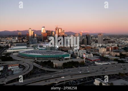 Dusk with moon rising over the mountains behind downtown Los Angeles skyline aerial Stock Photo