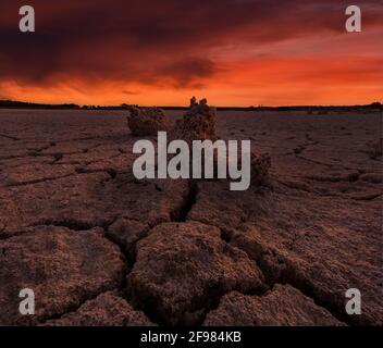 Drought landscape with cracks in ground without water with red sky Stock Photo