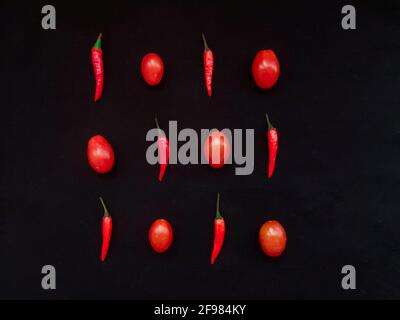 Red hot chili peppers and cherry tomatoes on black background top view Stock Photo