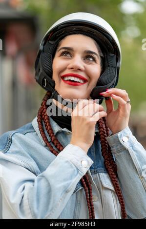Close-up of a young woman fastening a motorcycle protective helmet Stock Photo