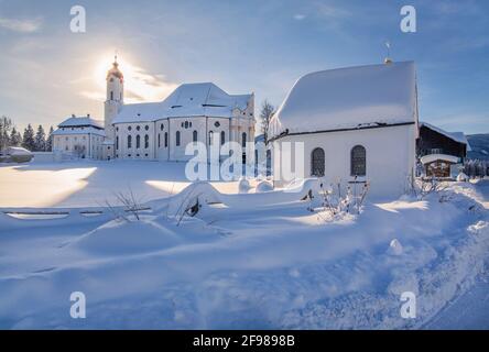 Winter landscape with a small chapel and the pilgrimage church Wieskirche in the district of Wies, Steingaden, Pfaffenwinkel, Romantische Strasse, Upper Bavaria, Bavaria, Germany Stock Photo