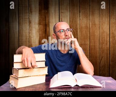 Tired and sleepy mature man on his books, studies to improve his economy. Stock Photo