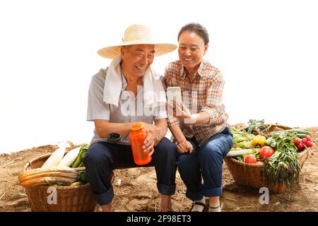 Peasant couple sat in the farm see a mobile phone Stock Photo