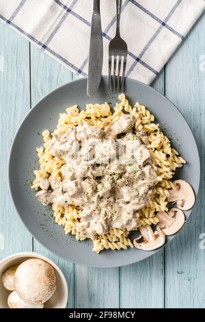 Tagliatelle Italian pasta with forest white champignon mushrooms creamy sauce and chicken or beef meat - homemade food in plate on the table top view Stock Photo
